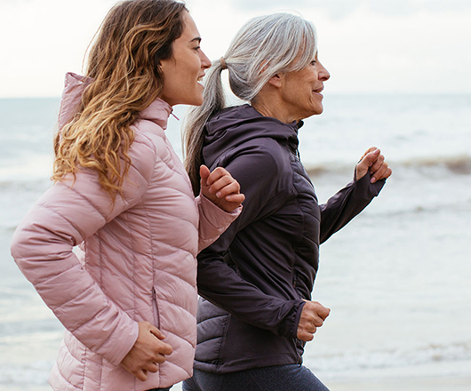 moeder en dochter joggen op het strand