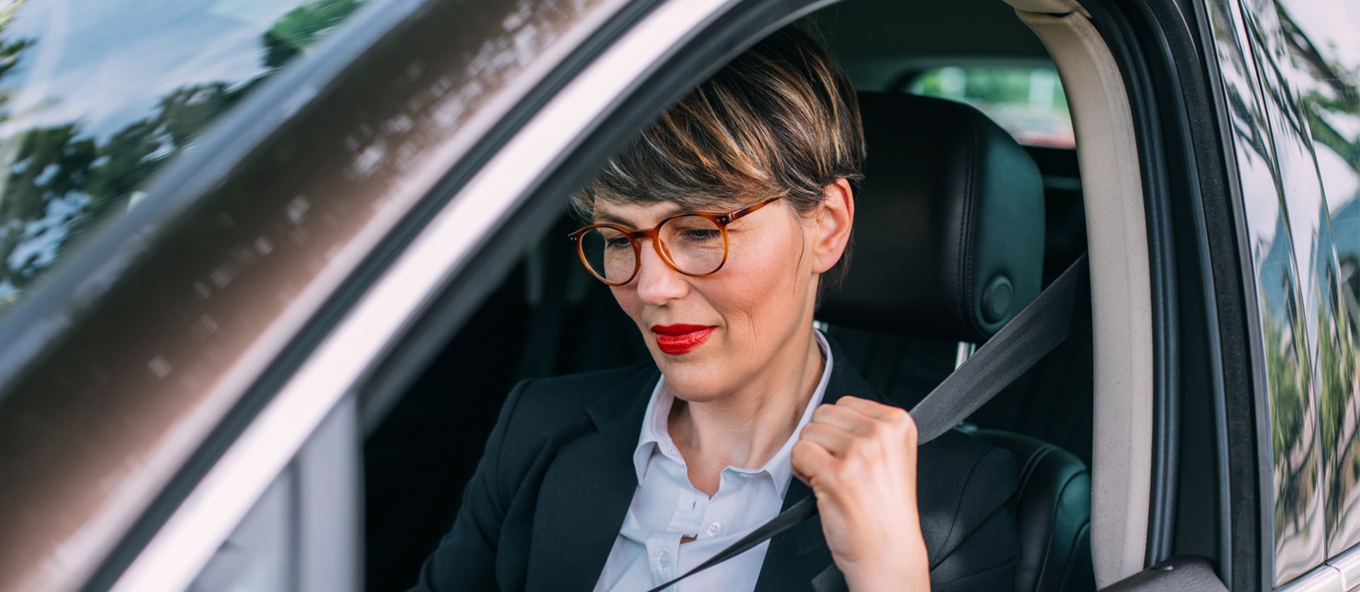 Vrouw zit achter het stuur en doet haar gordel om